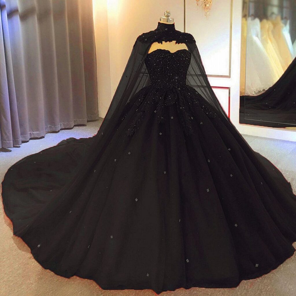 A black beaded wedding gown with a sheer cape displayed on a mannequin.