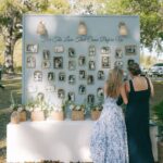 Two women viewing a nostalgic photo display featuring many framed vintage family photographs outdoors.