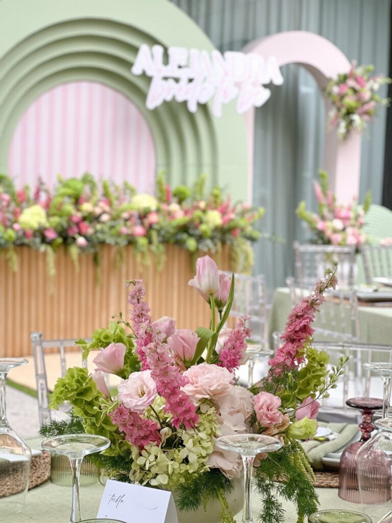 Pink and green floral centerpiece with roses and snapdragons on a wedding table.