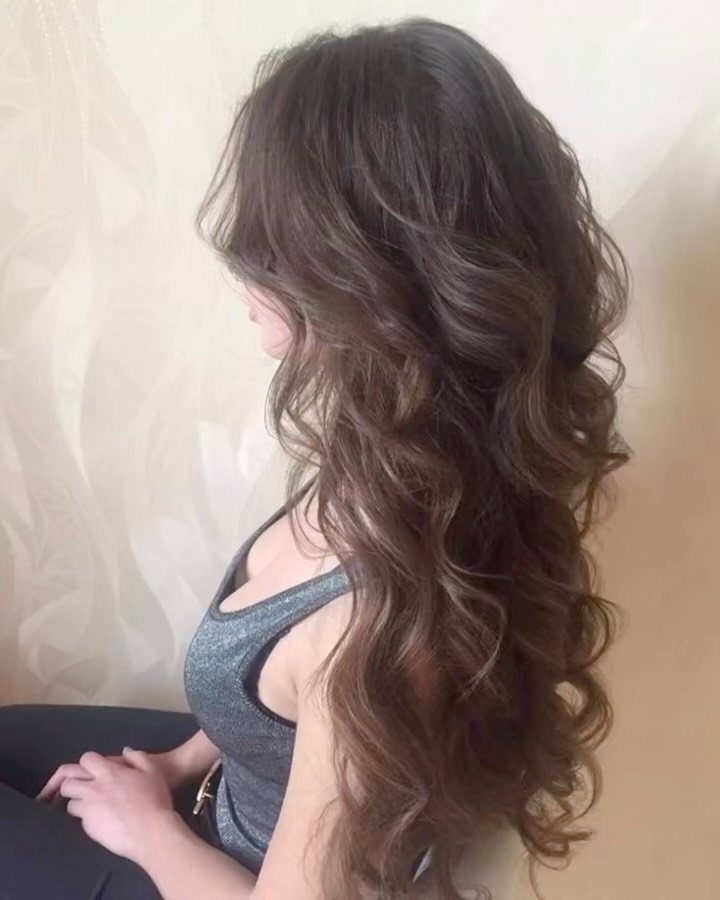Long brunette hair styled in voluminous, cascading curls falling down a woman's back.